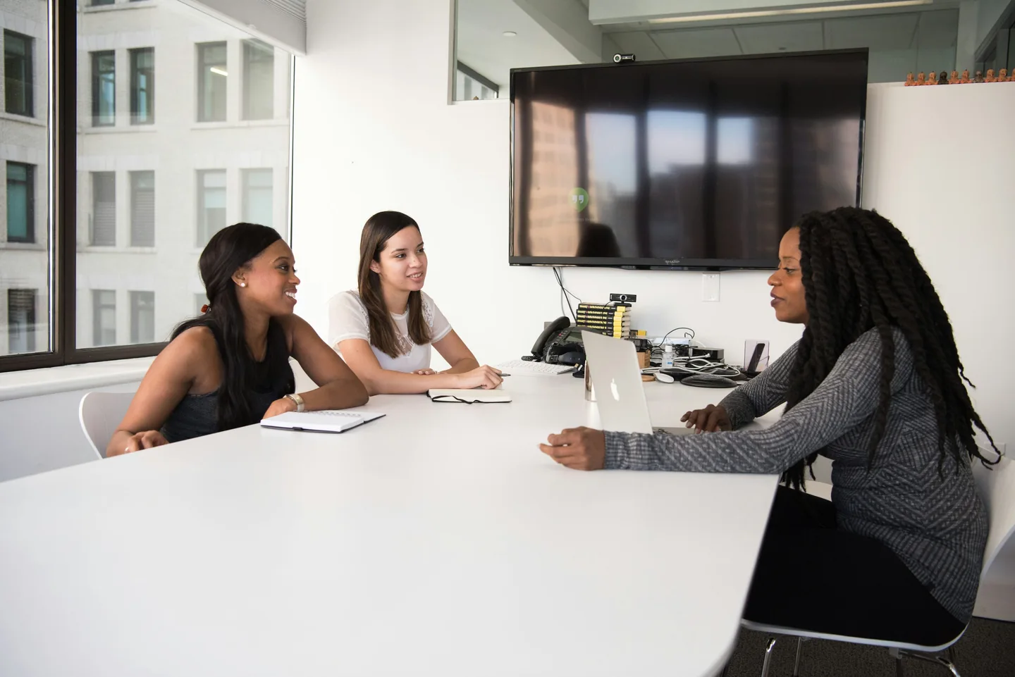Three women discussing work around a conference table