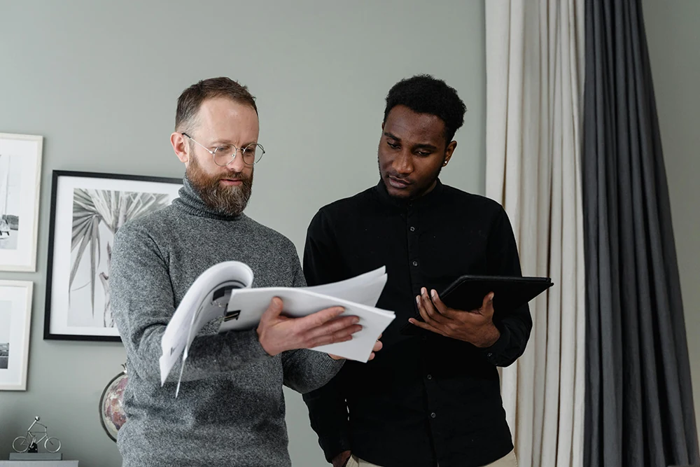 Two colleagues reviewing documents and a tablet together