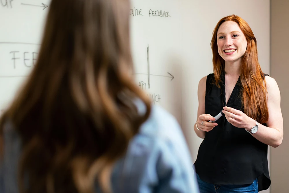 Colleagues discussing work beside a whiteboard